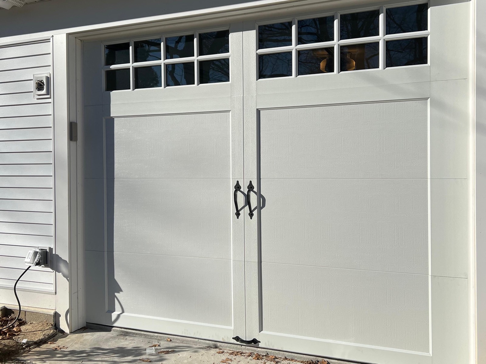 New white carriage-style insulated steel garage door on a ranch house