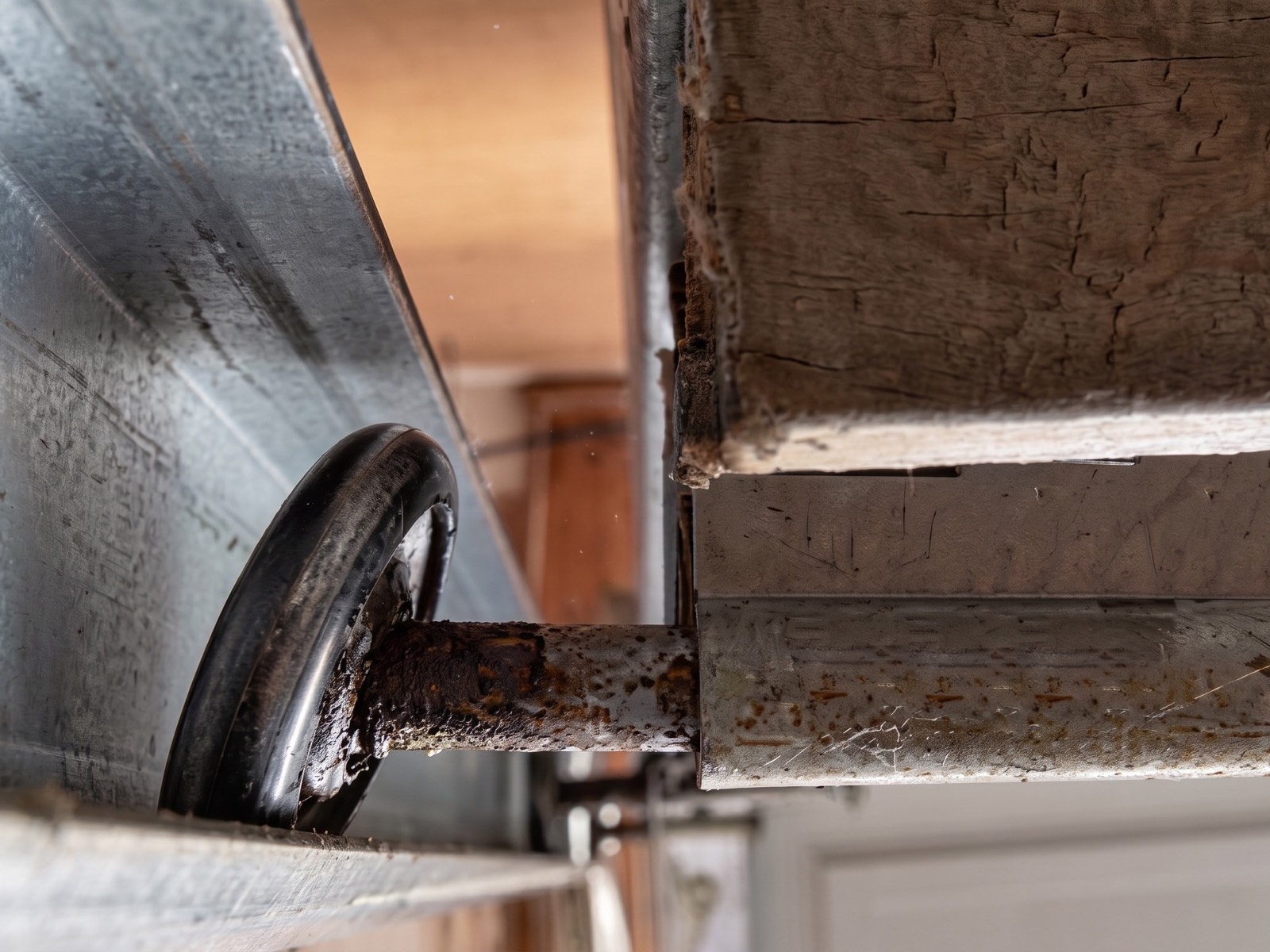 Worn garage door roller sitting outside a bent track
