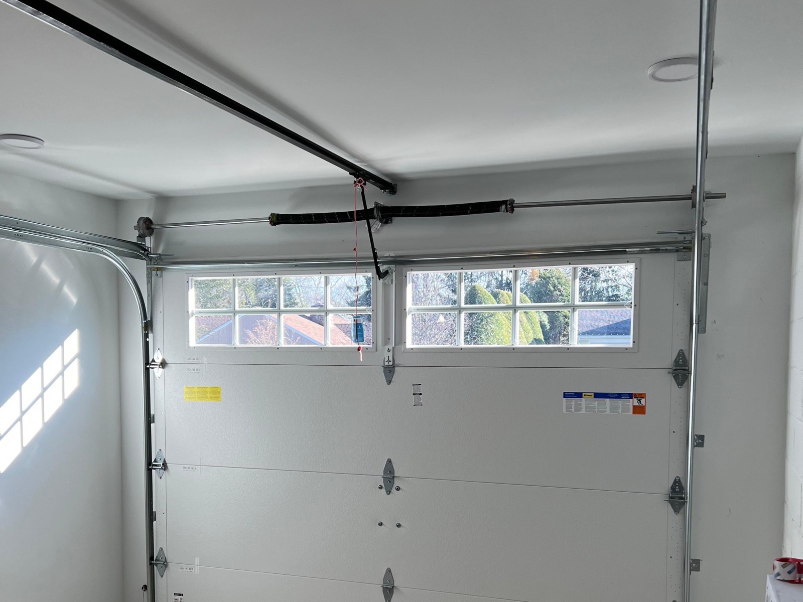 Torsion spring and cable drum mounted above a garage door