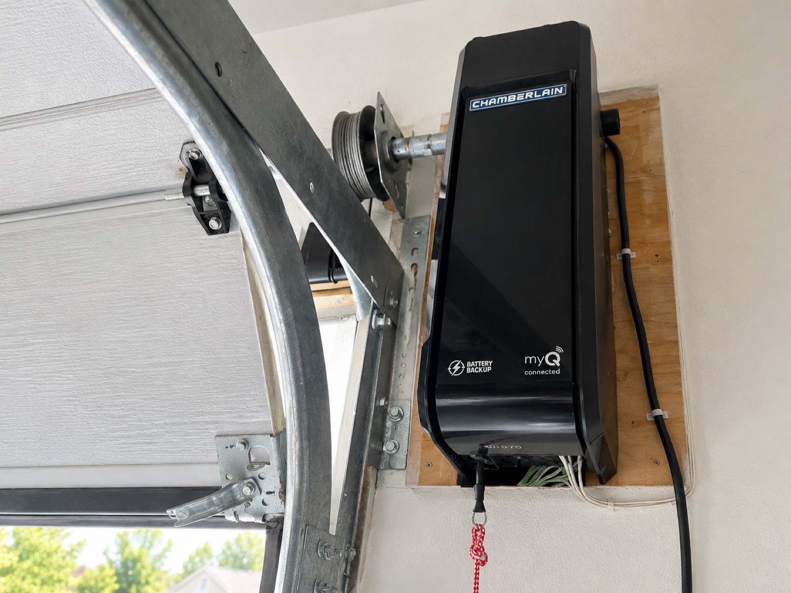 Wall-mount garage door opener with battery backup installed beside the door